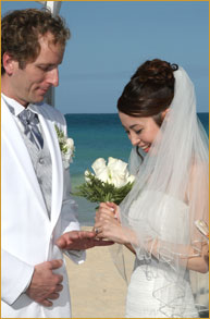 Couple exchanging wedding bands by the ocean